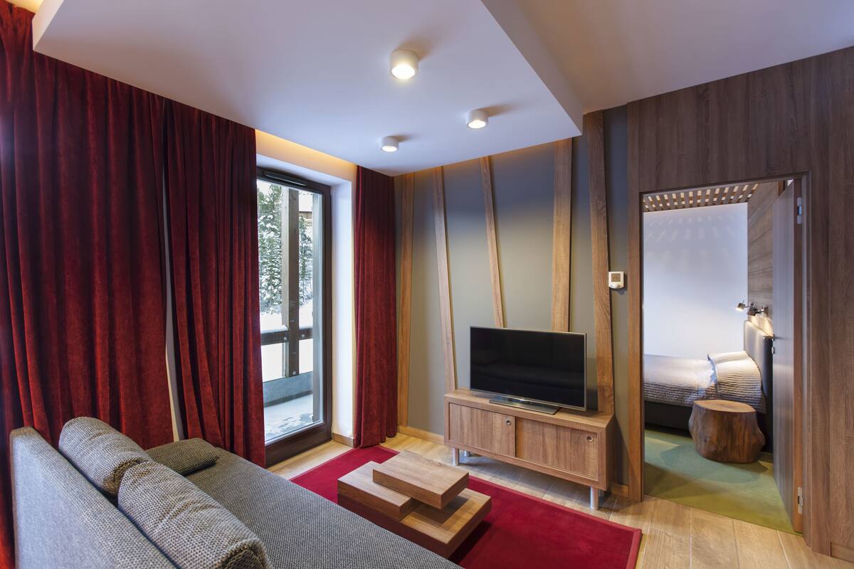 A modern living room with a sofa, a flat-screen TV, and a wooden cabinet.