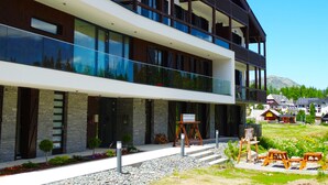 A modern two-story hotel with a balcony, stone facade, and a sign indicating it is a ski resort. - Apparthotel Silbersee (Stadl-Predlitz)