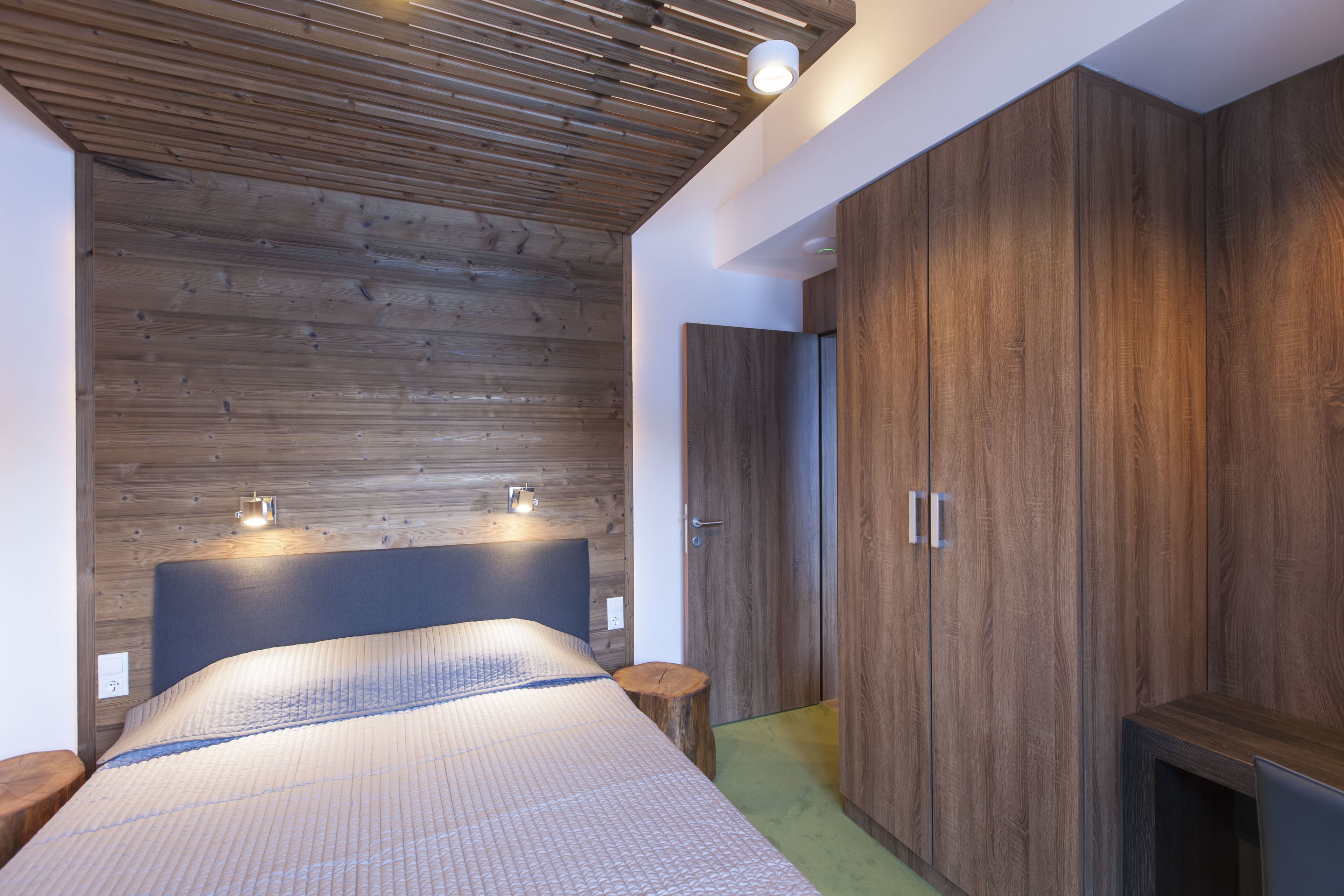 Ein modernes Schlafzimmer mit Holzboden, einem großen Bett mit blauer Kopfteil und eingebauten Holzausbau.