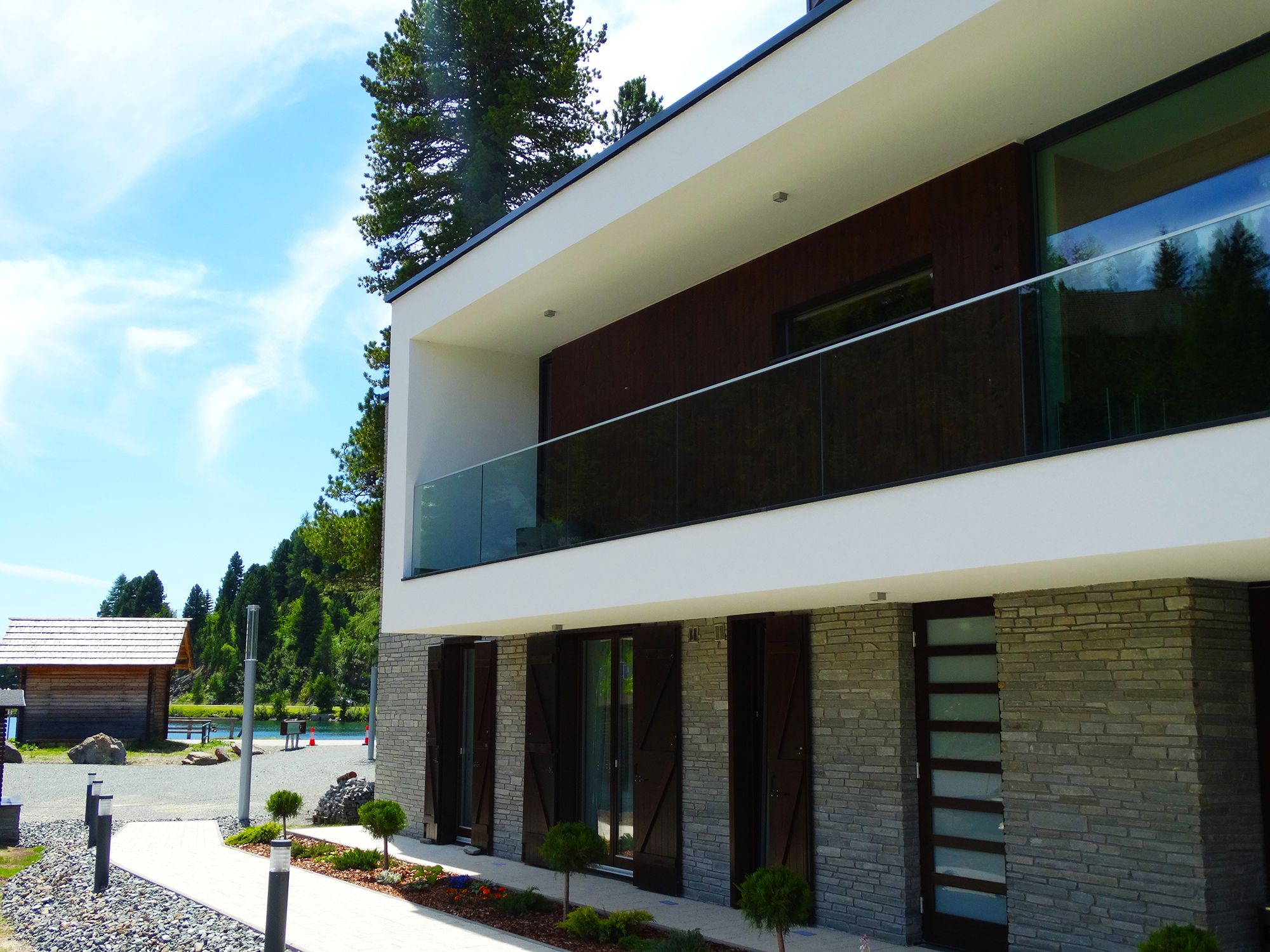 A modern two-story building with a flat roof, large windows, and a stone facade.