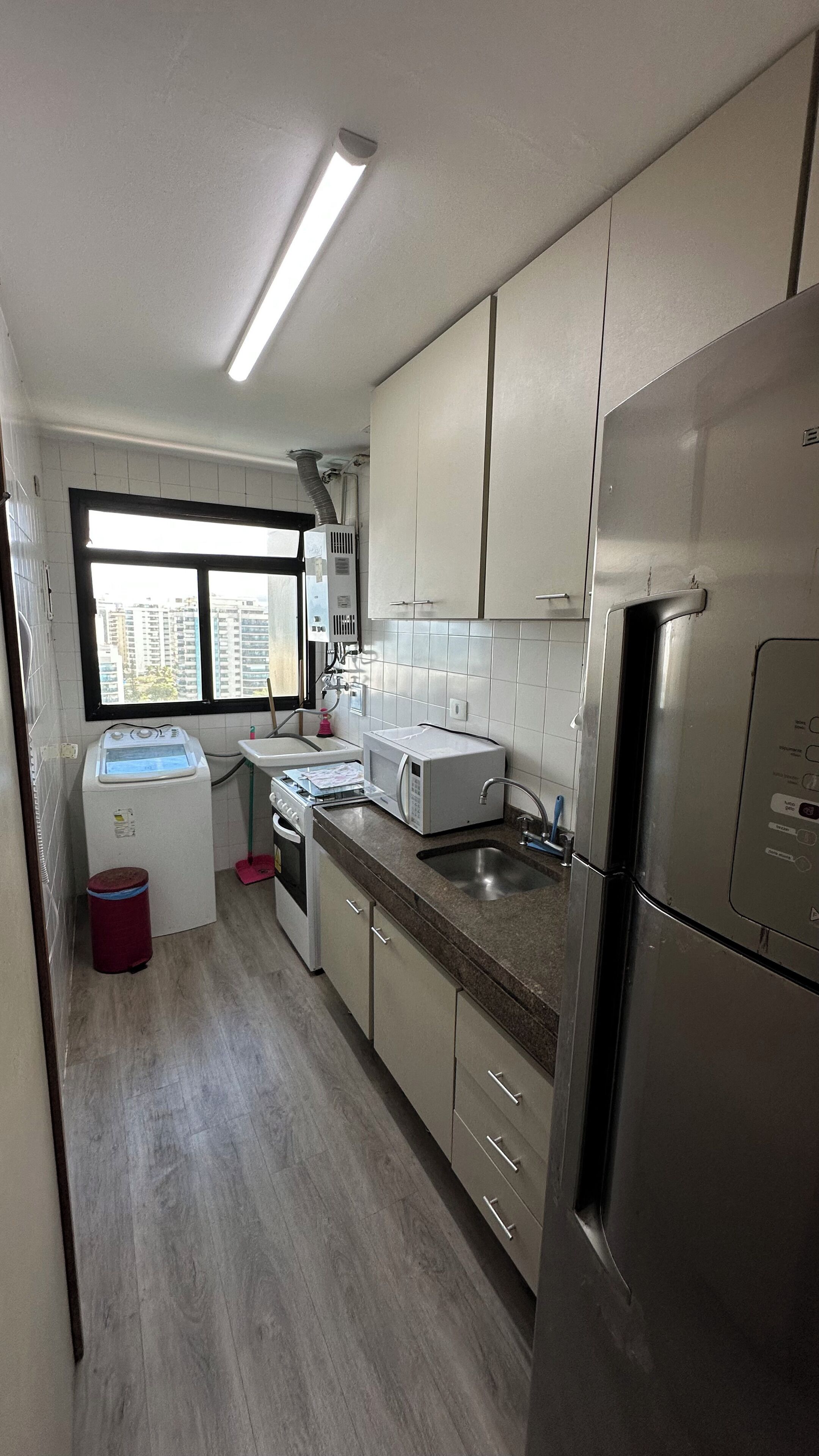 A compact kitchen with a microwave, sink, and stainless steel refrigerator.