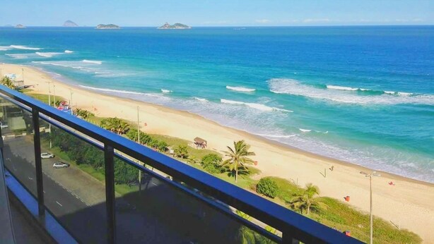 A beach view from a balcony with a clear sky, ocean waves, and distant islands. - Flat Barrabella (Rio de Janeiro)