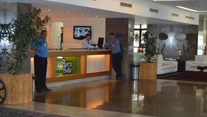 A hotel reception area with a reception desk, two staff members, and a modern interior design. - Flat Barrabella (Rio de Janeiro)