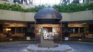 A hotel entrance with a sign reading "Barra Bella" and a covered seating area in front. - Flat Barrabella (Rio de Janeiro)