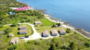 Vista aérea de una propiedad costera con varias casas, una carretera y una playa.