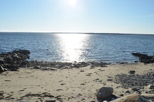 A beach with a rocky shoreline and calm water reflecting sunlight.
