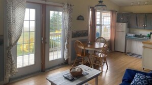 Un comedor con mesa y sillas, una cocina con armarios y un refrigerador, y una vista por la ventana.
