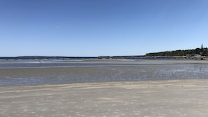 Una playa con una extensa zona arenosa y un mar tranquilo.