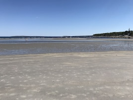 A beach with a wide sandy area and a calm sea.