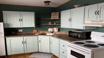 Una cocina con armarios azul claro, estufa blanca, microondas y fregadero.