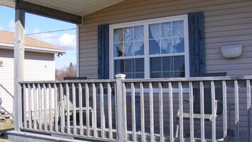 A house with a porch, a window with blue shutters, and a white mailbox on the wall.