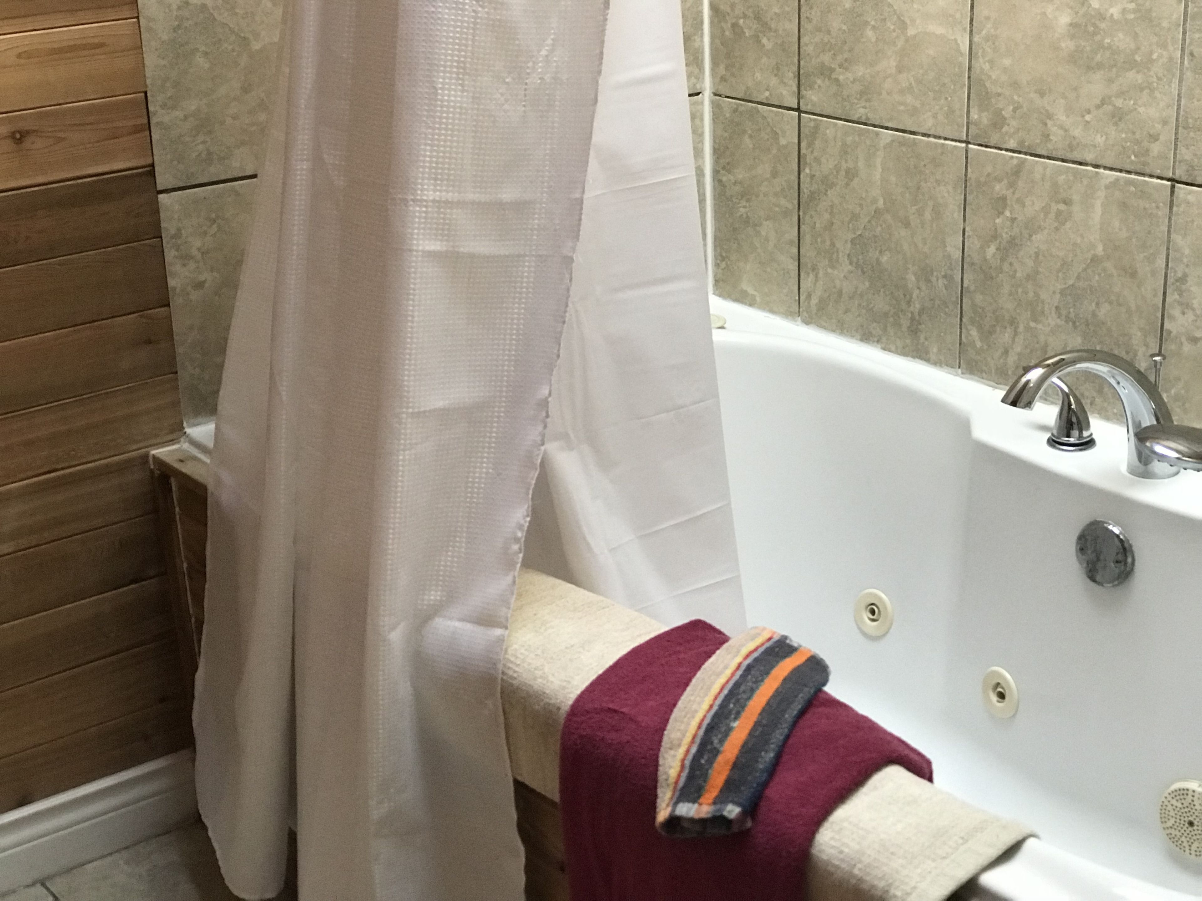 Ein Badezimmer mit einer Badewanne, einer Duschvorhang und einem Handtuchhalter mit einem Handtuch.