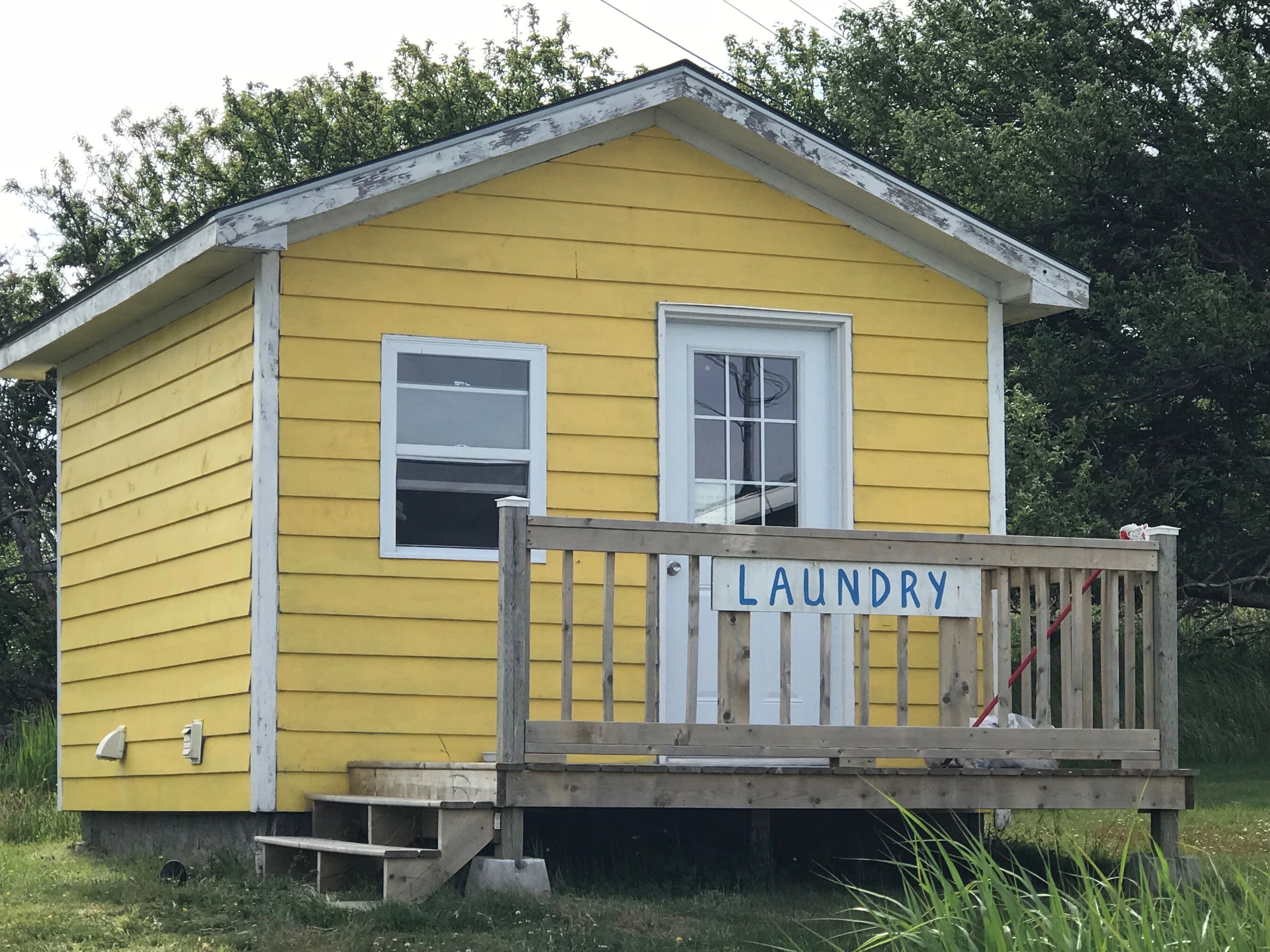 A yellow laundry building with a wooden deck and a sign that reads "LAUNDRY".