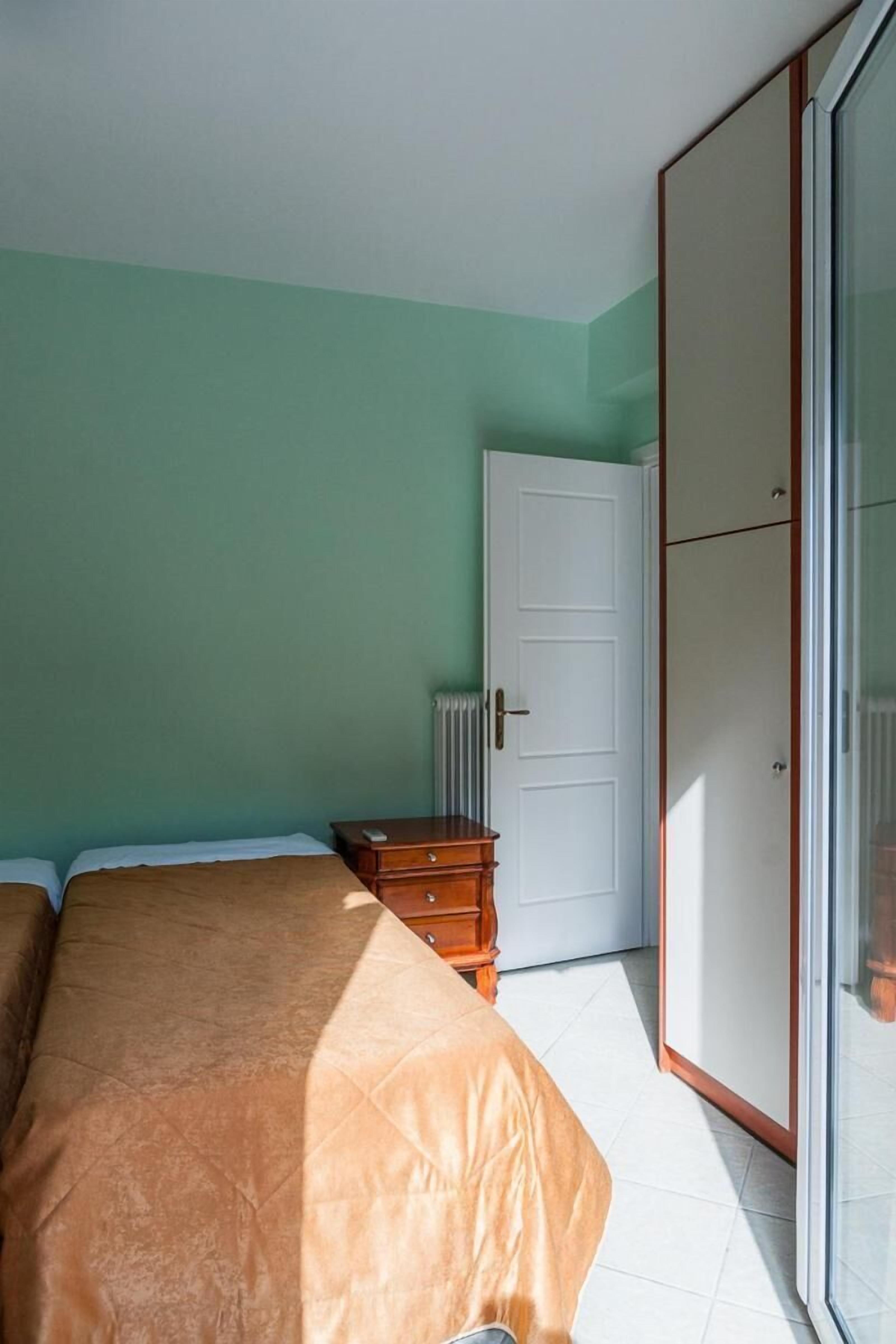 Une chambre à coucher comprenant un lit, une commode, une armoire et un radiateur.