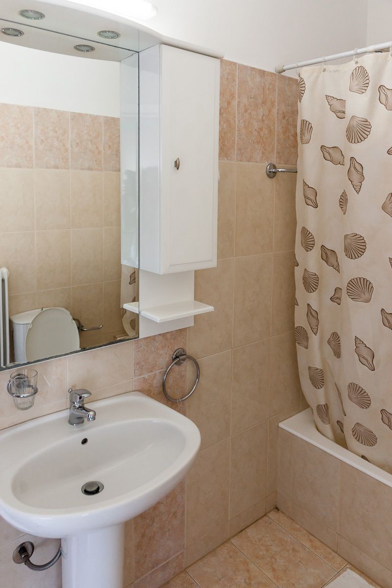 Ein Badezimmer mit Waschbecken, Spiegel und Duschvorhang.