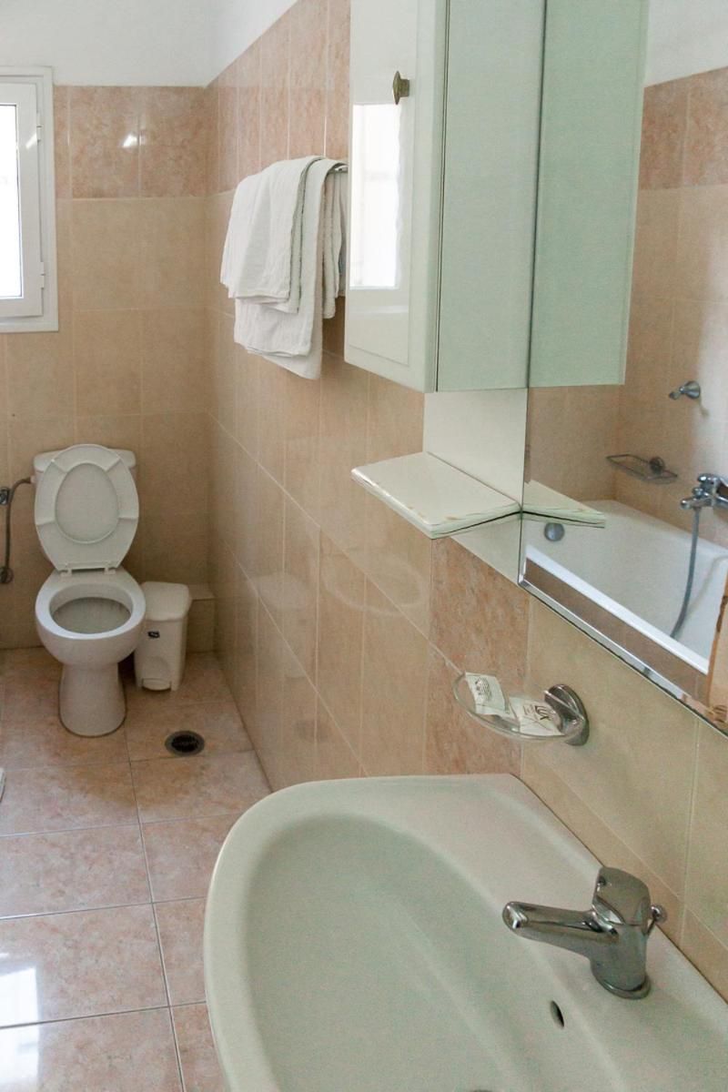 A bathroom with a toilet, sink, and mirror.