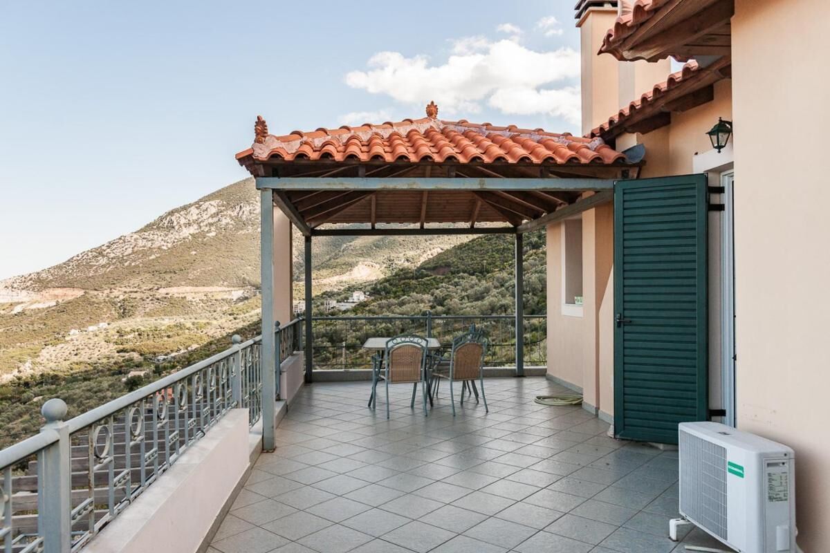 A covered outdoor area with a table and chairs, a green door, and an air conditioning unit.
