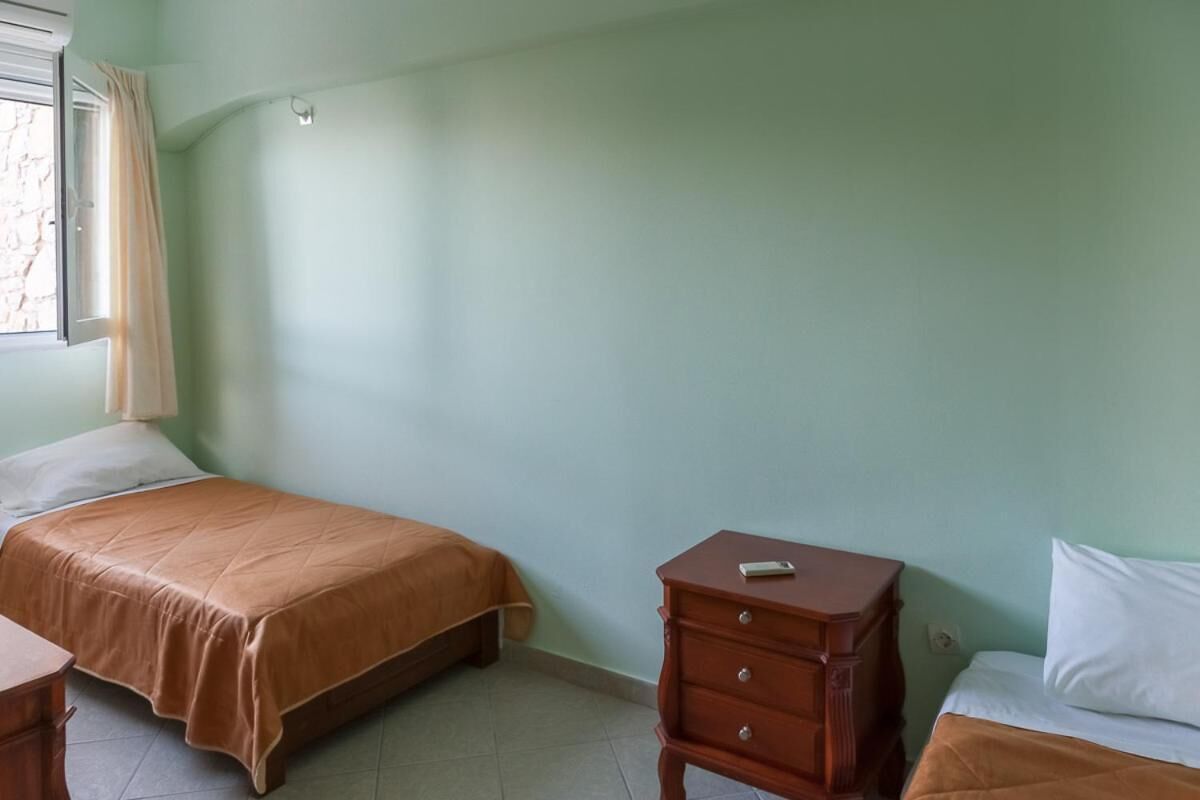 Une chambre avec deux lits, une table de chevet en bois et une fenêtre avec des rideaux.