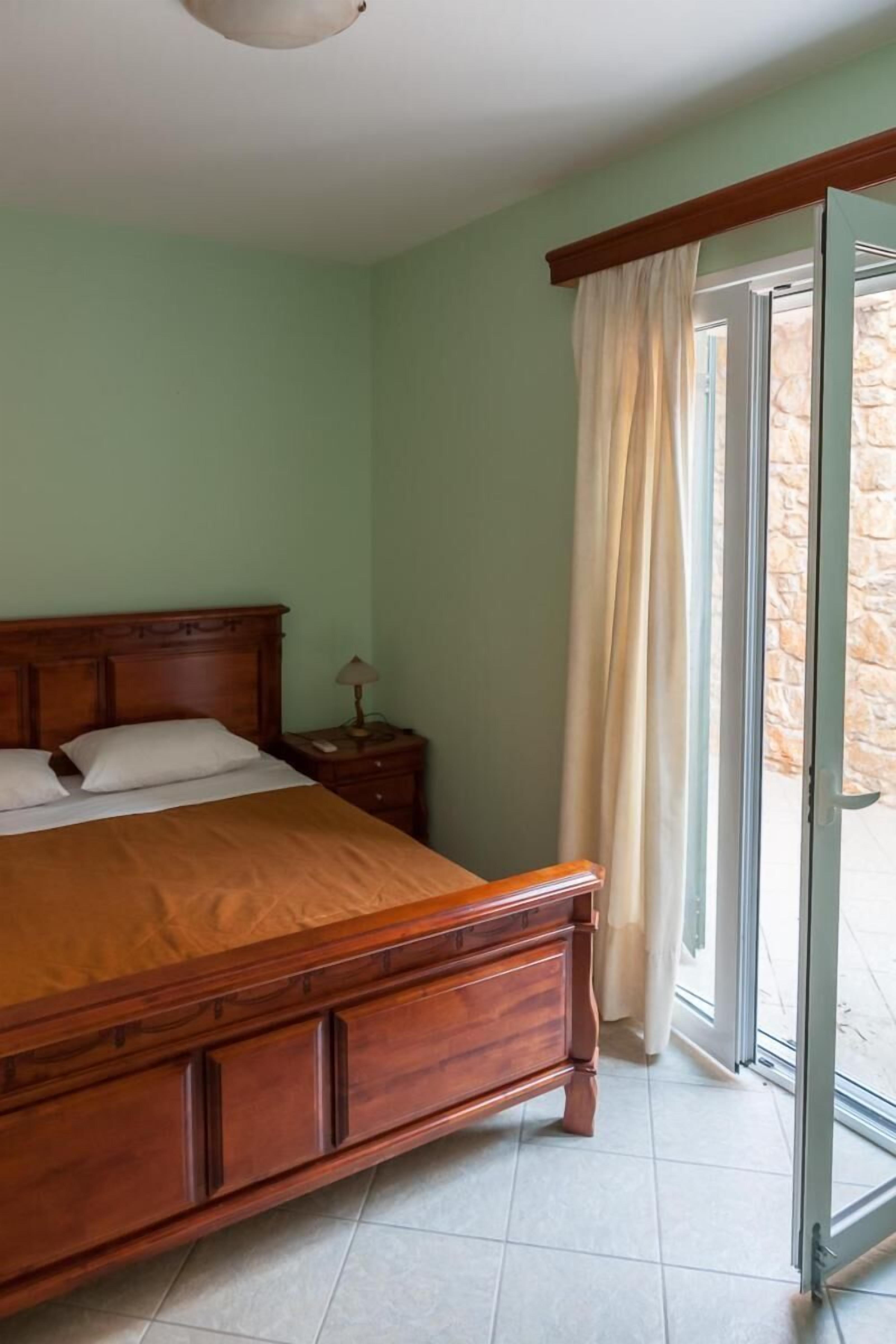 Une chambre à coucher avec un lit en bois, une table de chevet et une fenêtre avec des rideaux.