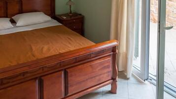 Une chambre à coucher avec un lit en bois, une table de chevet et une fenêtre avec des rideaux.