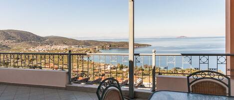 A terrace with a view of the sea and hills, featuring a table and chairs.