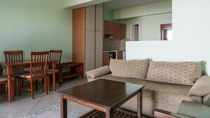 A living room with a sofa, a coffee table, and a dining area with chairs and a table. - Epidavros Seascape (Epidaurus)