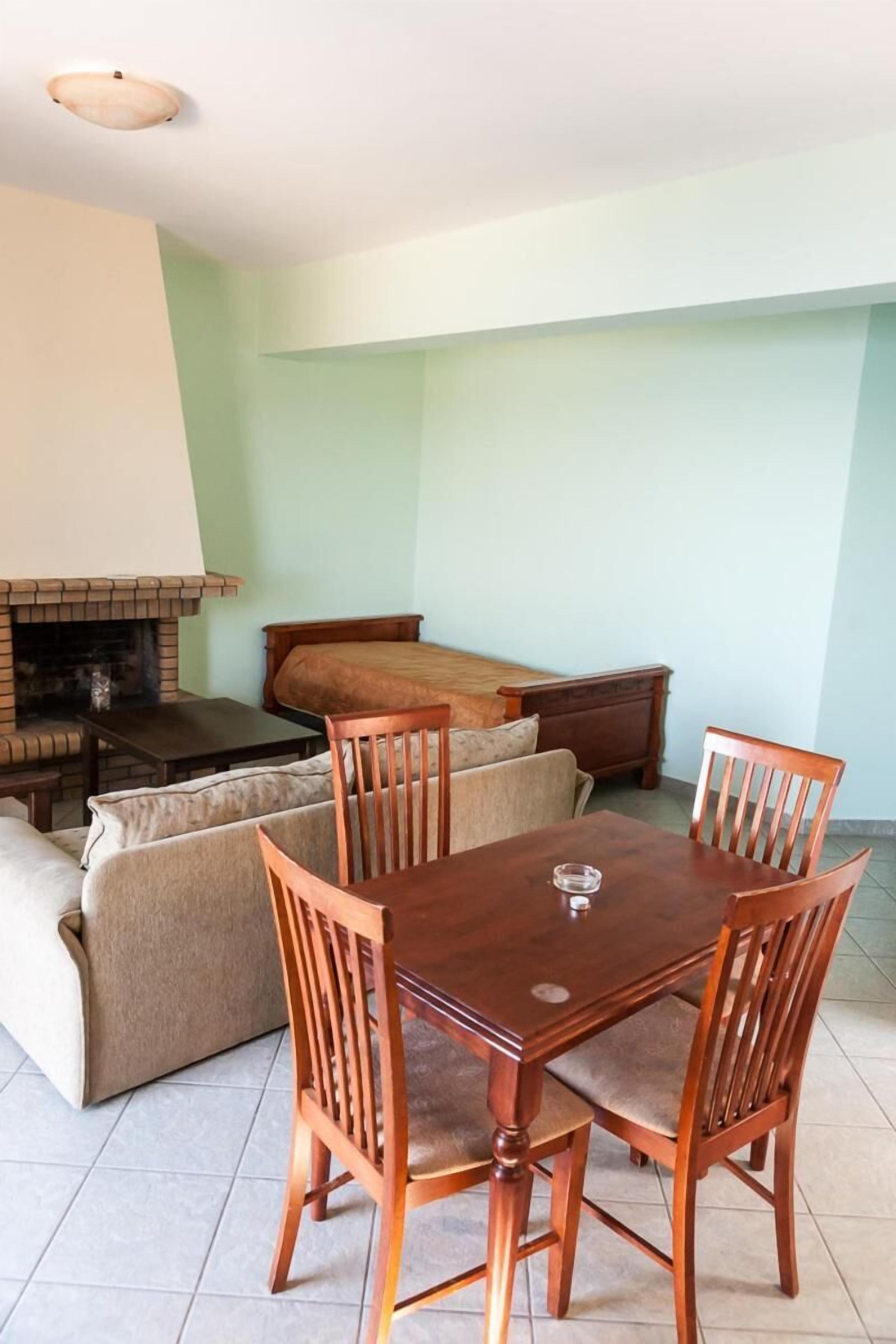 A dining area with a wooden table and chairs, a sofa, and a fireplace.