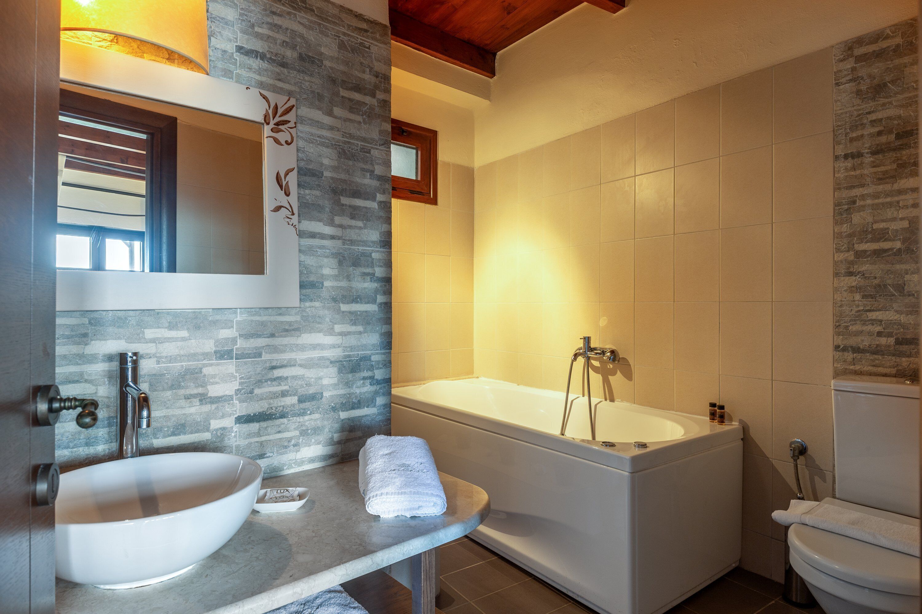 Ein modernes Badezimmer mit einer großen weißen Badewanne, einem Waschbecken und einem Spiegel darüber.