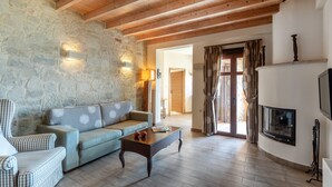 Una sala de estar acogedora con pared de piedra, vigas de madera, un sofá, una mesa de centro y una chimenea.