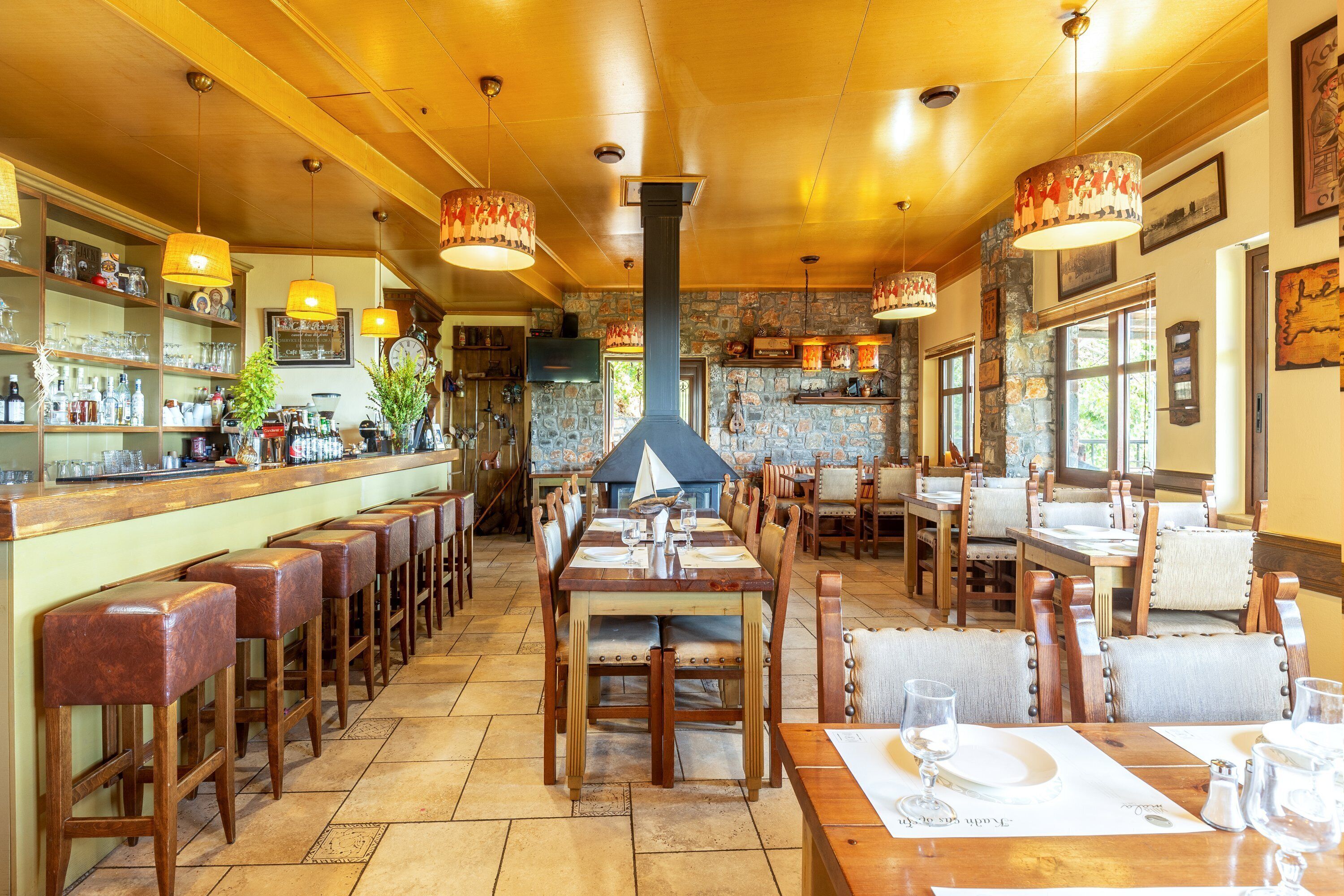 Een restaurant met houten tafels en stoelen, een bar en een stenen muur.