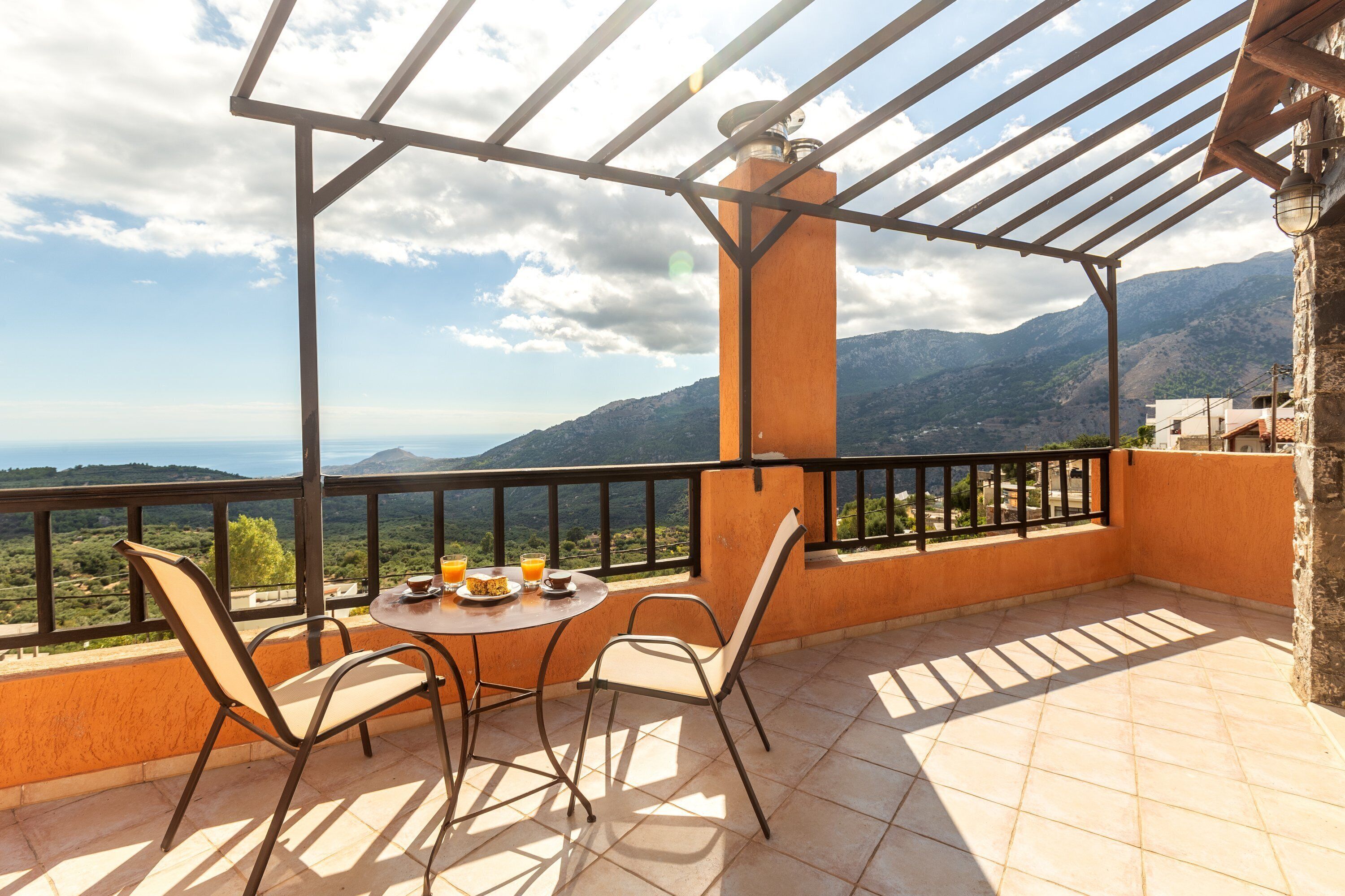 A terrace with a table and chairs, a view of mountains, and a pergola structure.