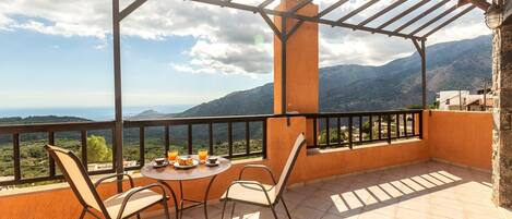 A terrace with a table and chairs, a view of mountains, and a pergola structure.