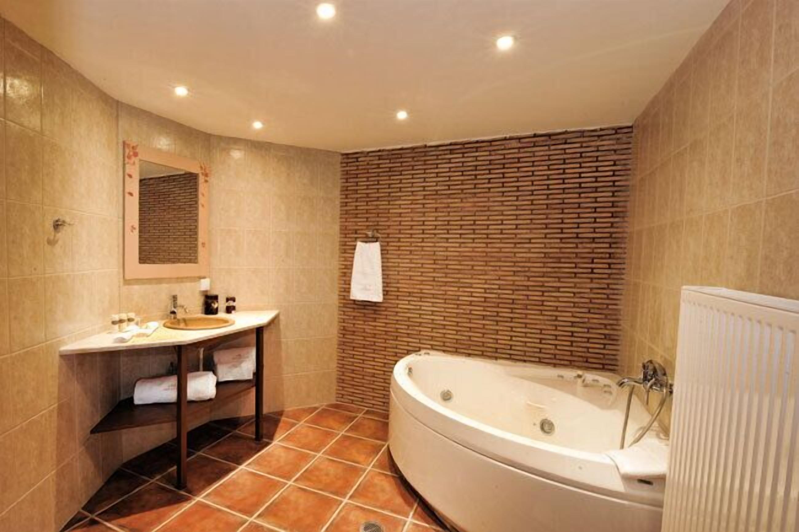Een badkamer met een vrijstaand bad, een wastafel met spiegel en een handdoekhouder.