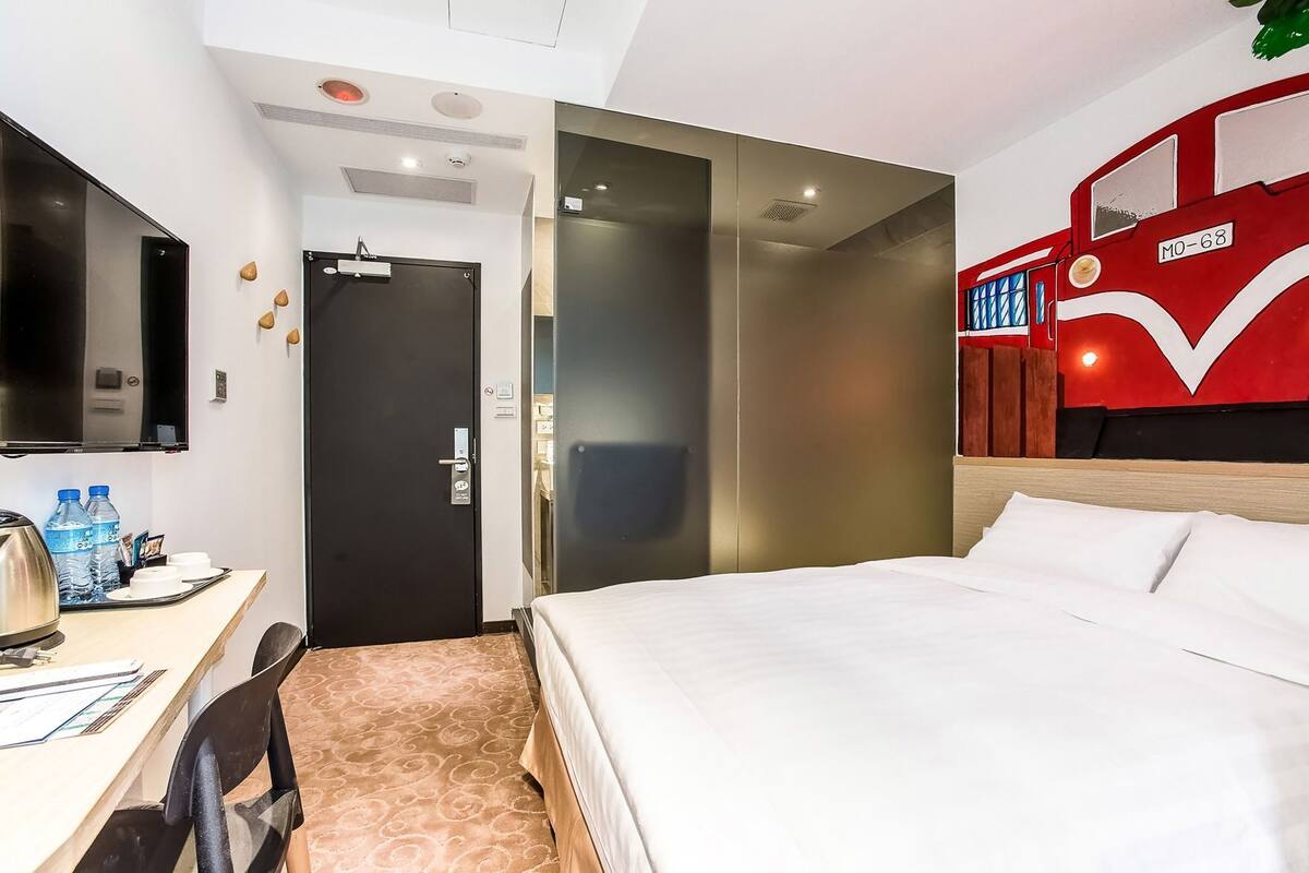 Una habitación de hotel con cama, escritorio, silla y televisor.