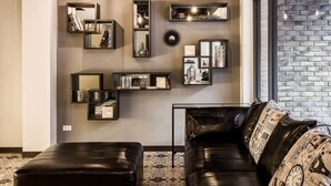 Uma sala de estar moderna com um sofá de couro preto, uma mesa de centro e uma parede de tijolos.