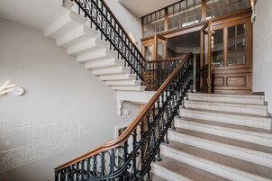 A staircase with white steps and black iron railings, leading to a wooden door with glass panels.