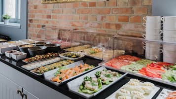 Un buffet proposant une variété de plats, notamment des sushis, des salades et d’autres mets, présentés dans des récipients transparents.