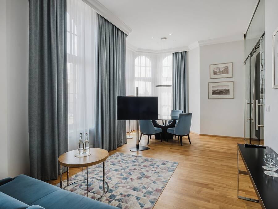 Ein modernes Wohnzimmer mit einer Couch, einem Couchtisch, einem Fernseher und einem Essbereich mit Stühlen und einem Tisch.