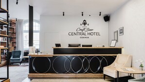 A reception area with a Craft Beer Central Hotel sign, a reception desk, a seating area with a chair, and a bookshelf. - Craft Beer Central Hotel (Gdansk)