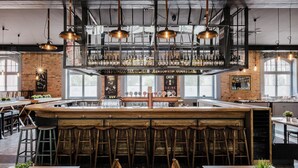 A bar area with multiple stools, a wooden counter, and a variety of bottles on shelves. - Craft Beer Central Hotel (Gdansk)