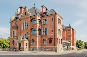 A large, historic brick building with arched windows and a prominent entrance.