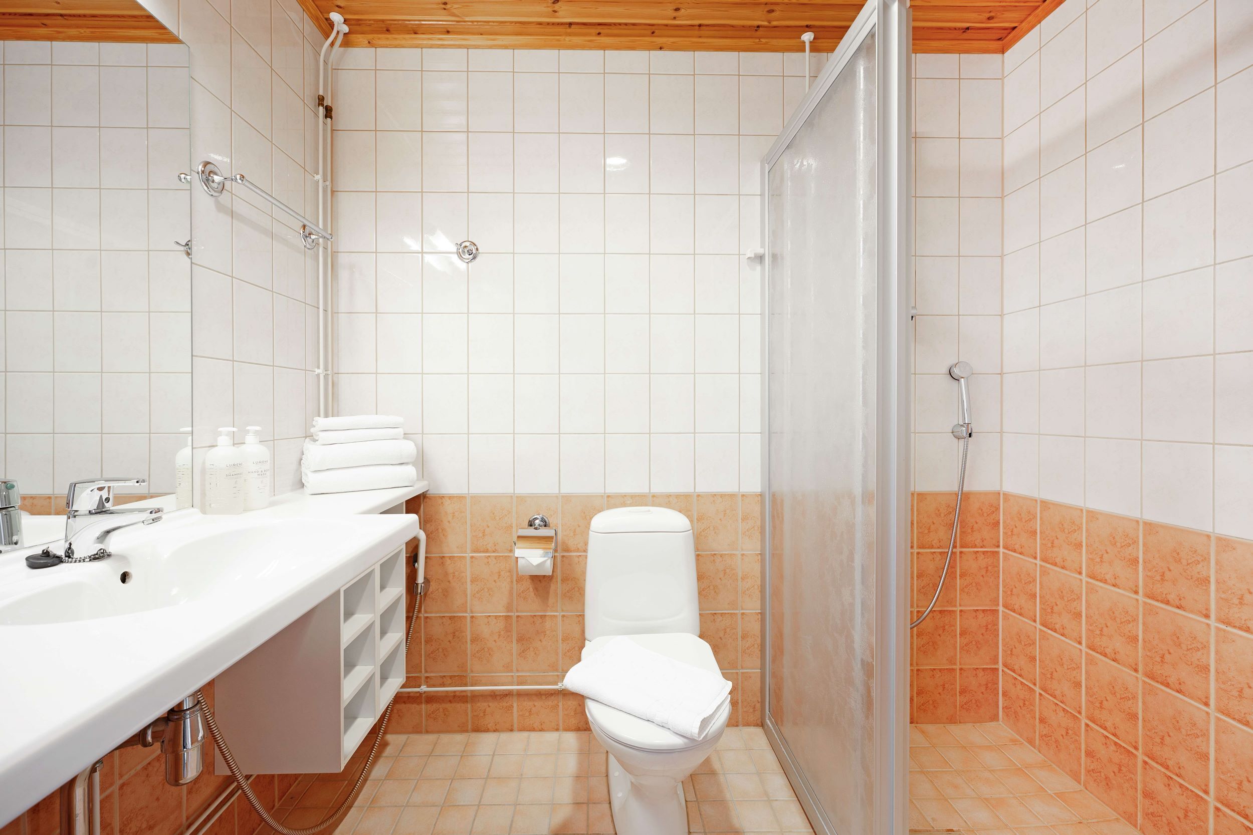 Et badeværelse med hvid vask, toilet og bruseniche.