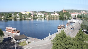 A riverside town with a large body of water, a bridge, and a prominent church tower. - Summer Hotel Tott (Savonlinna)