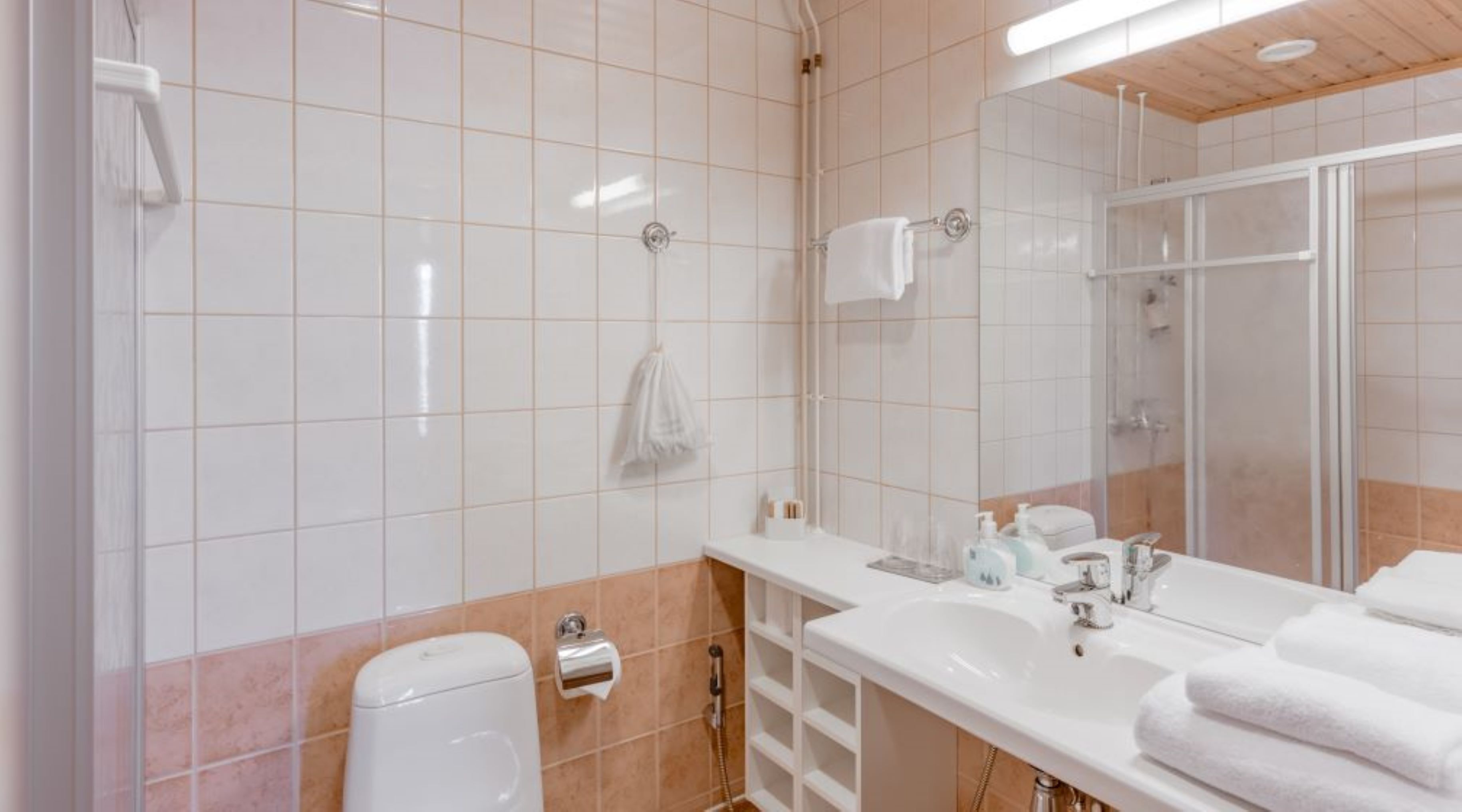 A modern bathroom with a large mirror, white sink, and a shower area.