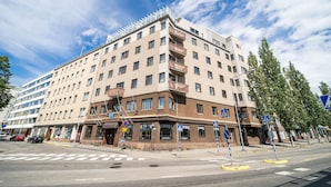A multi-story hotel with a modern design, featuring balconies on the upper floors, a pedestrian crossing, and a clear sky. - Summer Hotel Tott (Savonlinna)
