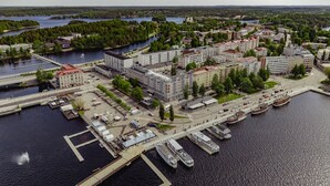 An aerial view of a riverside cityscape with buildings, docks, and boats. - Summer Hotel Tott (Savonlinna)