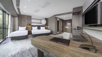 Une chambre d’hôtel moderne équipée de deux lits, d’un bureau, d’une télévision et d’une grande fenêtre.