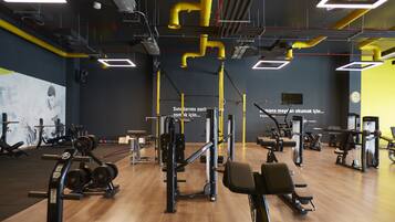 A gym with various exercise equipment, wooden flooring, and a large mirror on one wall.