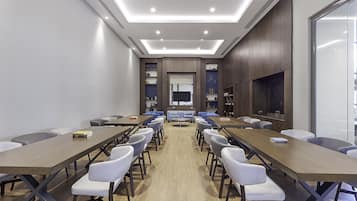 Uma sala de conferências com uma mesa comprida, várias cadeiras e uma tela de televisão.