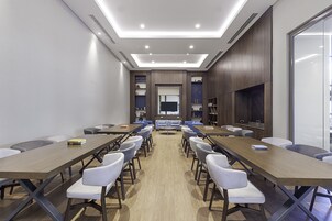Uma sala de conferências com uma mesa comprida, várias cadeiras e uma tela de televisão.